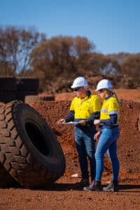 workers in PPE inspecting a large tyre