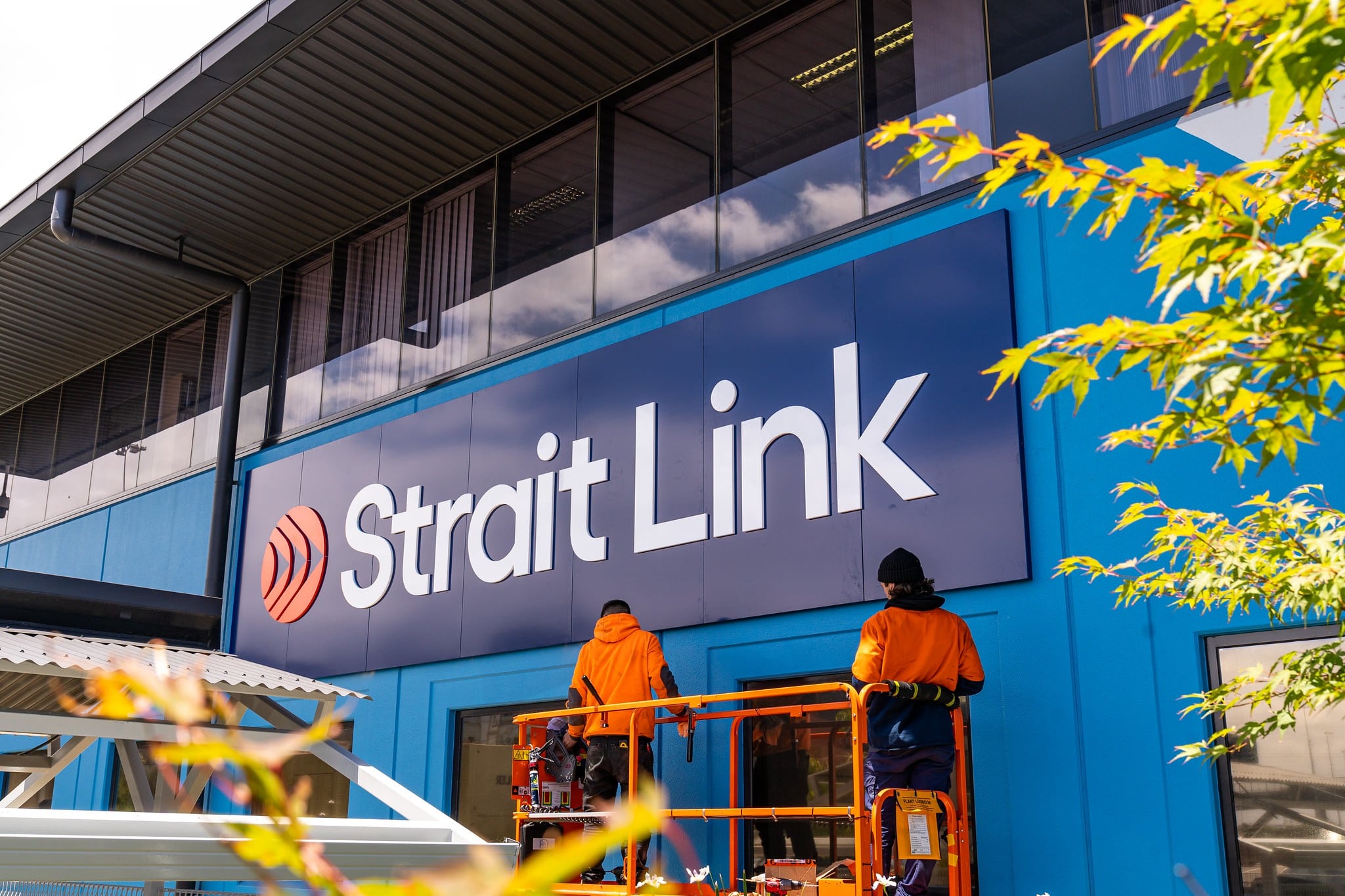 Strait Link signage and workers on an elevated platform creating video content